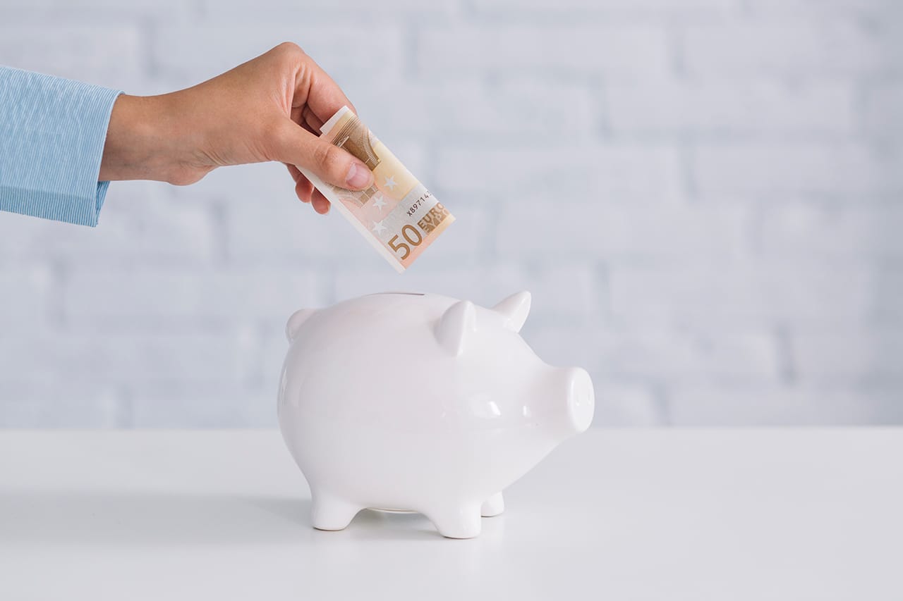 A woman inserting a 50 euro banknote into a piggy bank