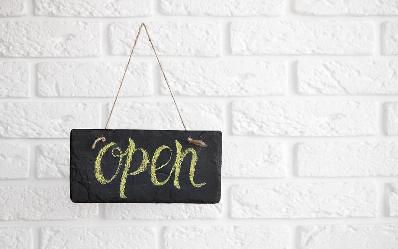 Open sign on a white brick wall background